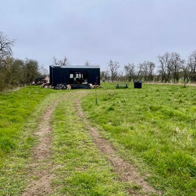 A single tiny house cabin painted entirely black situated in a meadow