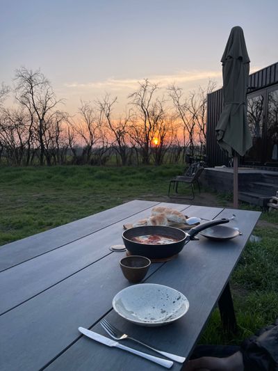 Eating dinner outside at a picnic table with a glowy pink sunset in the distance